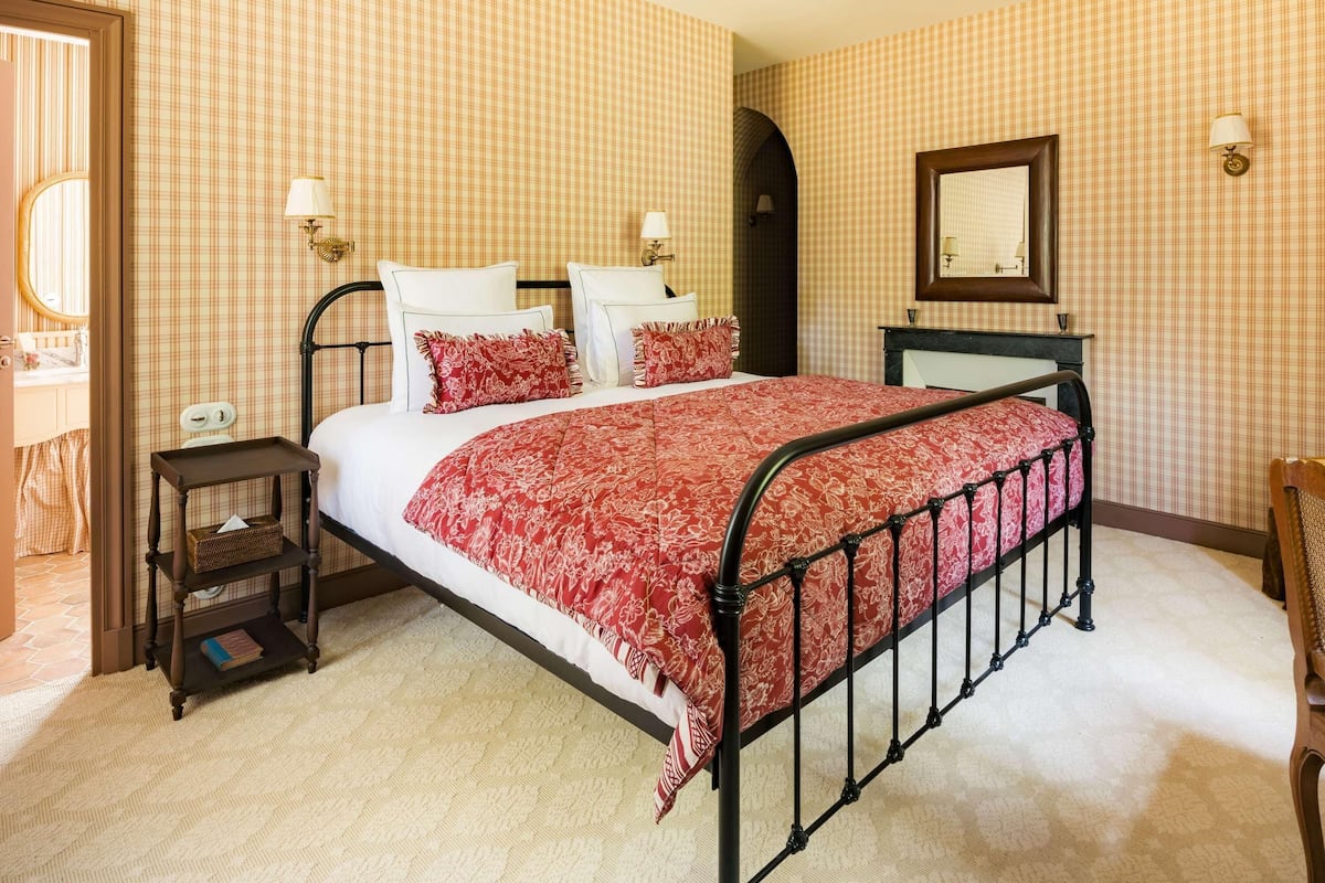 A bedroom with a bed, bedside tables, a dresser, a mirror, and a door.