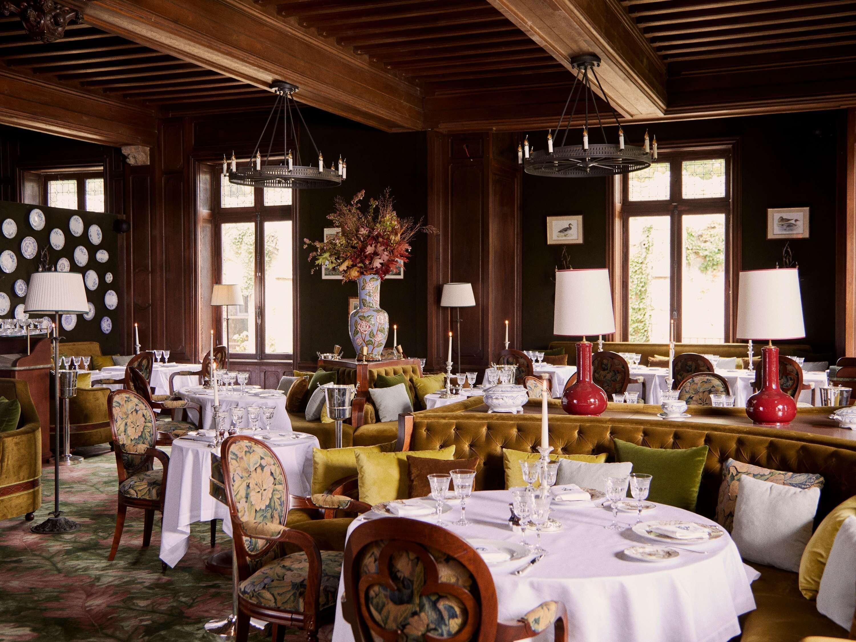 Un espace repas avec plusieurs tables dressées pour le service, des sièges rembourrés et une variété d'articles de table.
