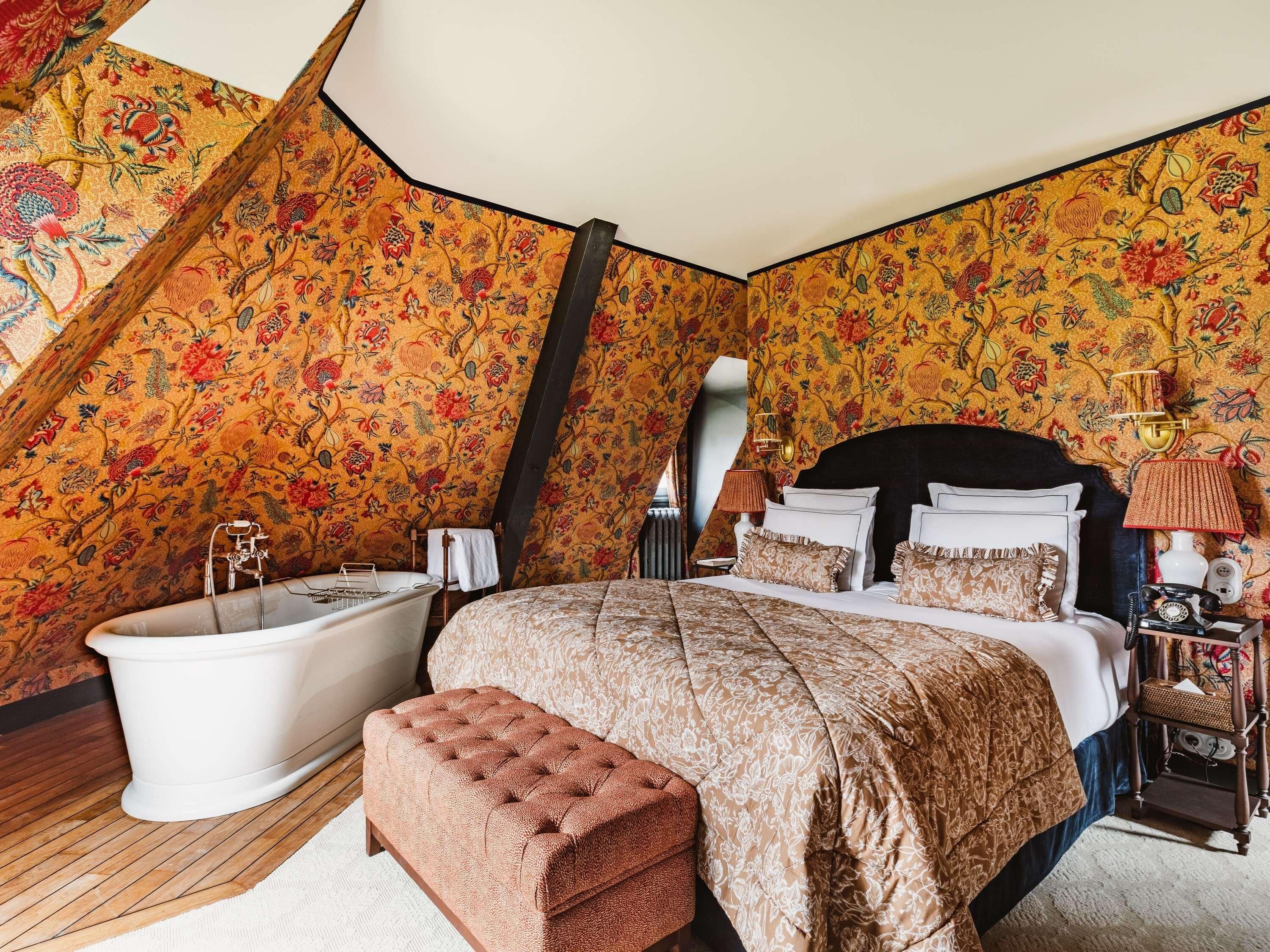 A bedroom with a large bed, a bathtub, and a wooden bench.