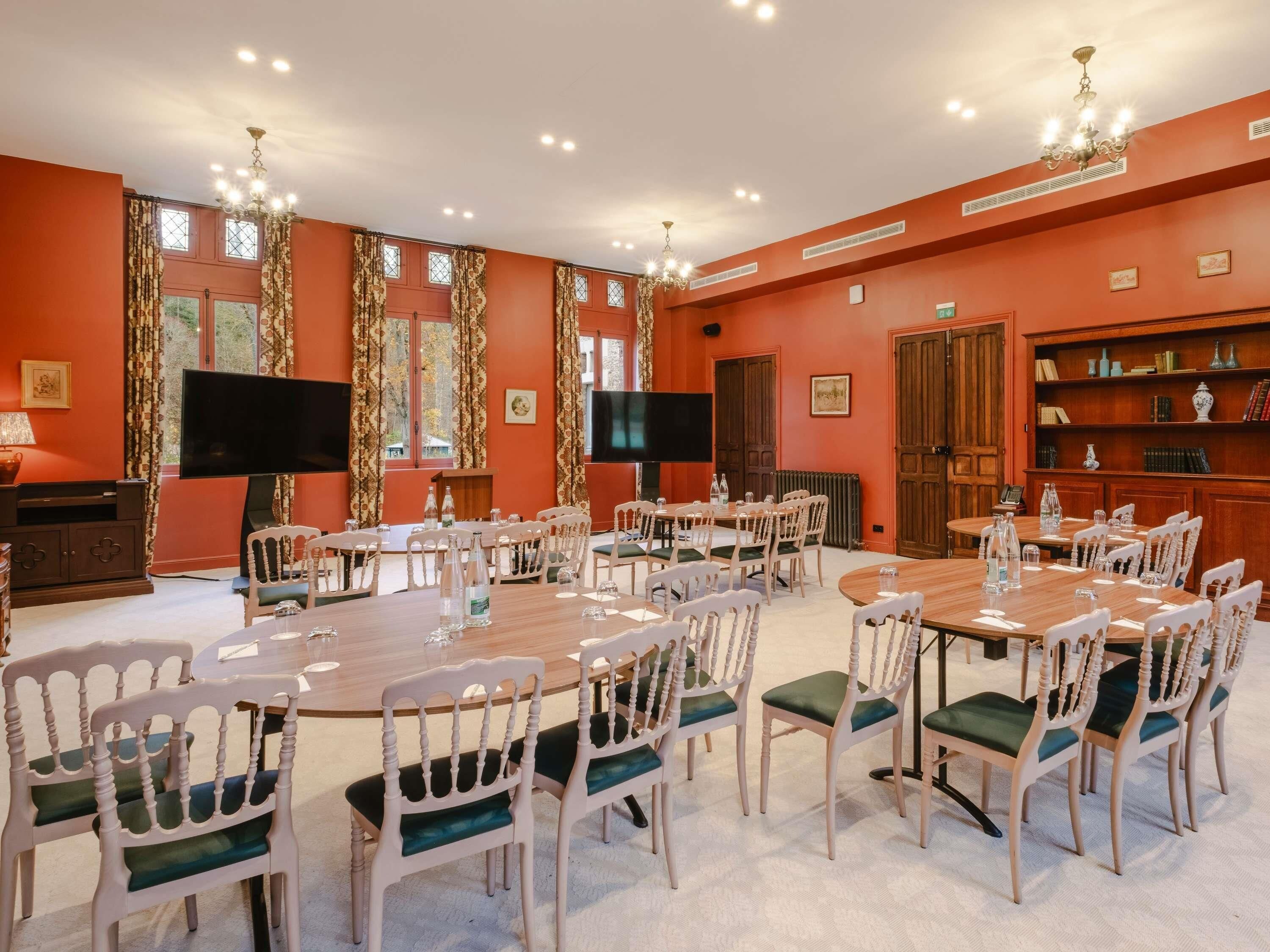 A conference room with multiple tables and chairs, a television, and a bookshelf with books and decorative items.