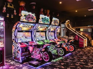 Máquinas de arcade con juegos de carreras y una escalera que sube a un nivel superior.