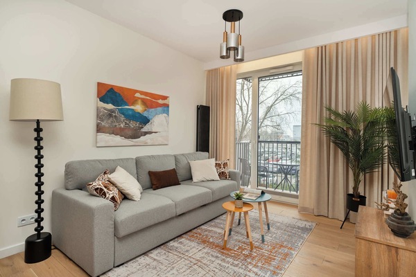 Bright living area with a comfortable sofa, coffee table, and direct access to the balcony. Large windows bring in plenty of natural light.