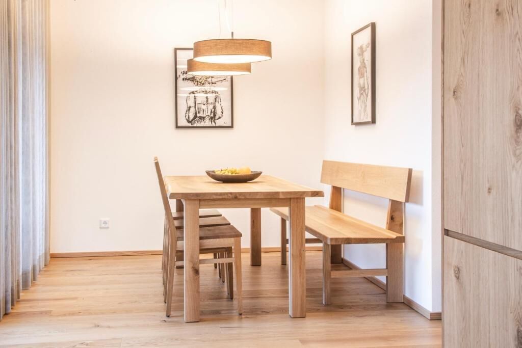 Un espace repas avec une table en bois, des bancs et un luminaire suspendu.
