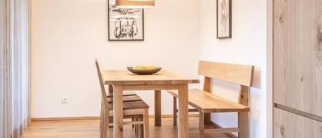 Un espace repas avec une table en bois, des bancs et un luminaire suspendu.