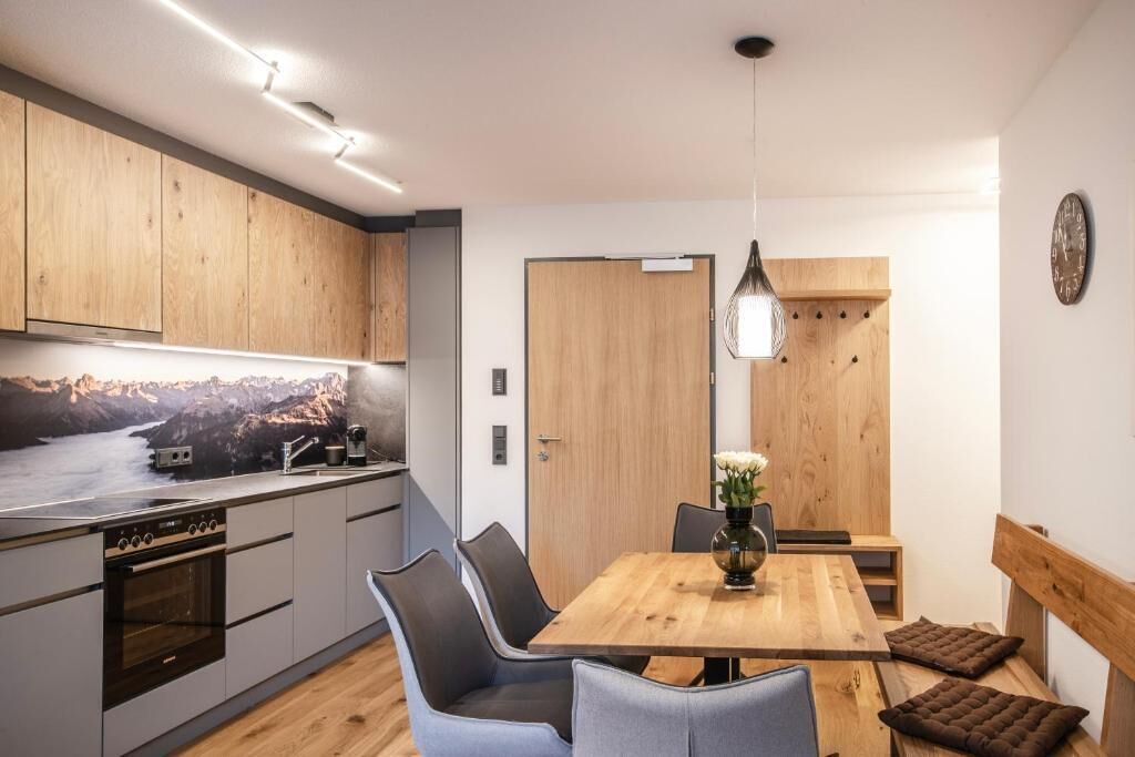 Eine moderne Küche mit Holzausstattung, einem eingebauten Ofen und einem Essbereich mit Holztisch und Stühlen.