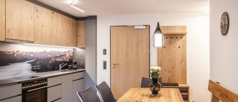Eine moderne Küche mit Holzausstattung, einem eingebauten Ofen und einem Essbereich mit Holztisch und Stühlen.