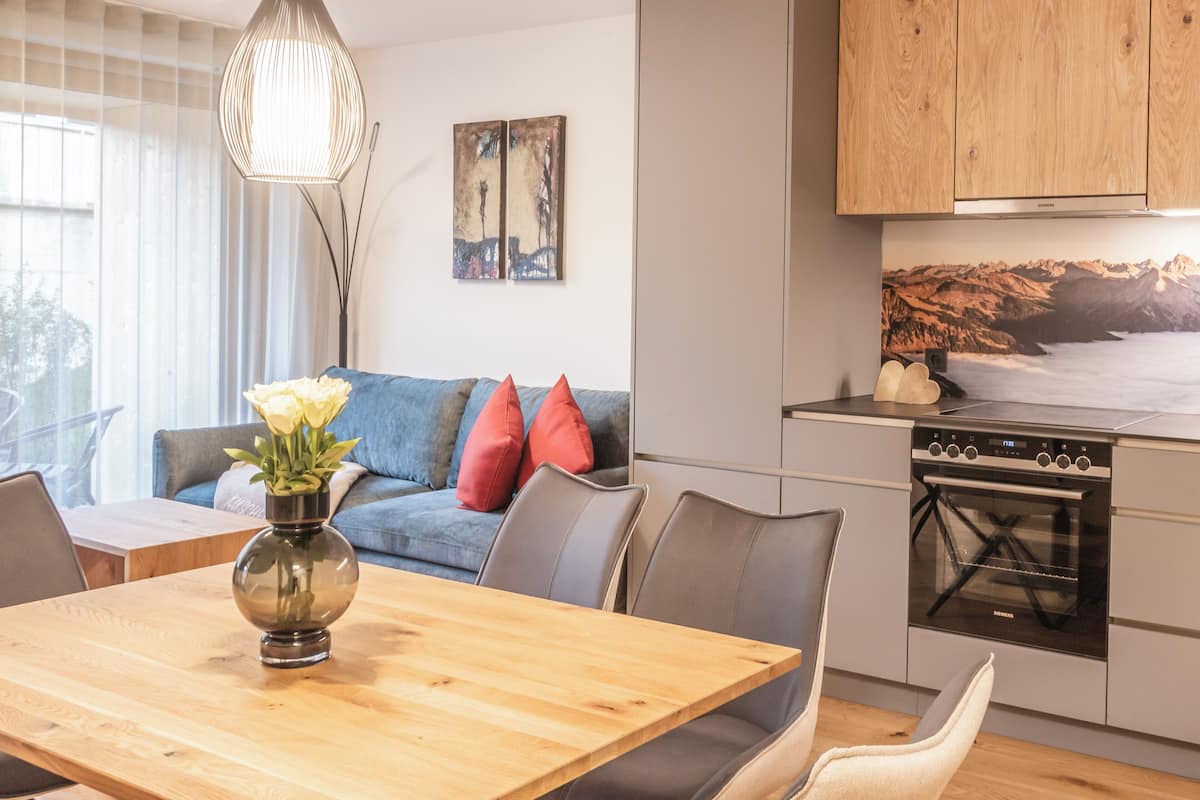 A modern kitchen with a built-in oven and a dining area with a wooden table and chairs.