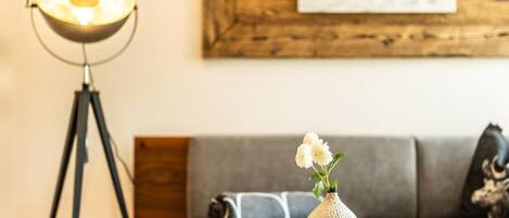 A modern living room with a sofa, a small round table with a vase of flowers, and a floor lamp.