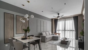 Una sala de estar moderna con comedor, un sofá seccional, un ventilador de techo y un amplio ventanal con cortinas.