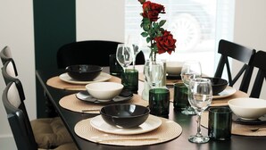 Une table à manger dressée avec des bols, des verres et un vase contenant une rose rouge.