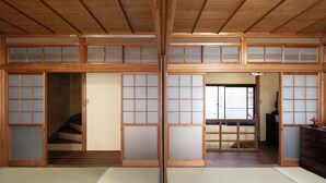 A traditional Japanese room with tatami flooring, sliding doors, and a wooden staircase.