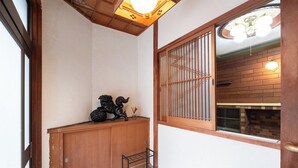 A traditional Japanese room with tatami flooring, a wooden door, and a sliding shoji screen.