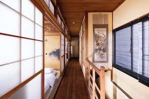 A traditional Japanese corridor with tatami mat flooring, sliding doors, and a wooden railing.