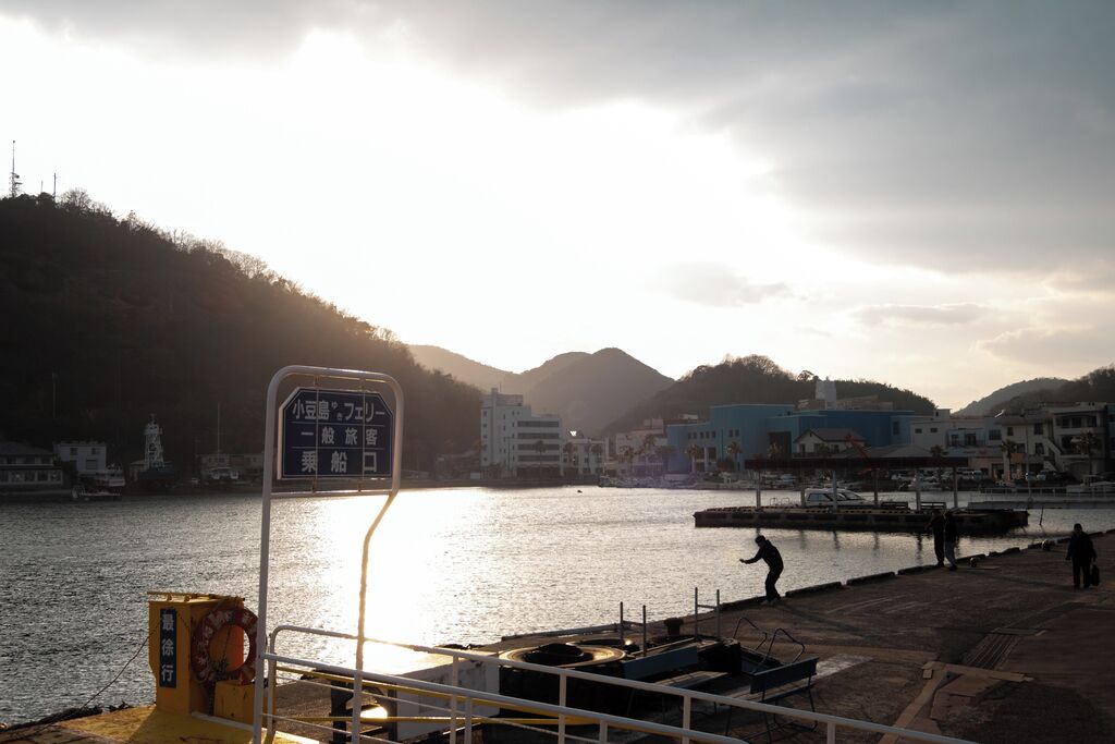 Un puerto con un muelle, un cartel y edificios al fondo.