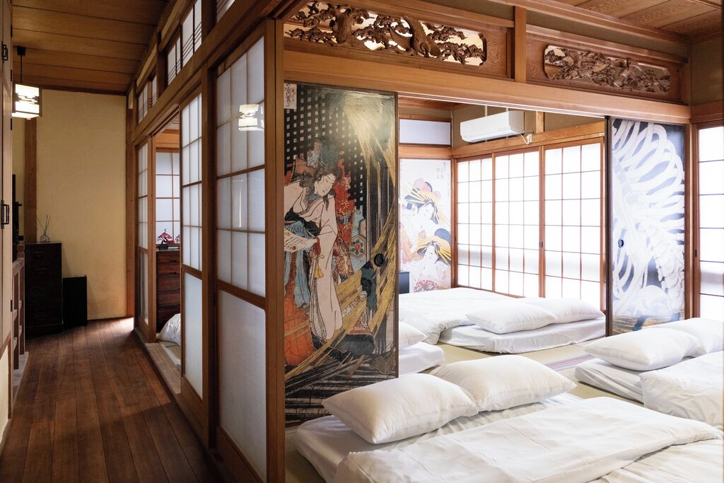 Una habitación japonesa tradicional con suelo de tatami, puertas correderas shoji y camas futón.