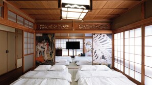 A traditional Japanese room with tatami flooring, shoji screens, and a futon bed arrangement.