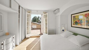 Un dormitorio con una cama grande, un aparador, un radiador y una ventana con cortinas.