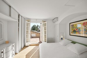 Ein Schlafzimmer mit einem großen Bett, einem Schminktisch, einem Heizkörper und einem Fenster mit Vorhängen.