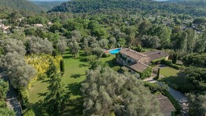 Una villa con piscina rodeada de exuberante vegetación y colinas al fondo.
