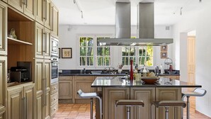 Una cocina amplia con una isla central, armarios de madera y un gran ventanal que proporciona luz natural.