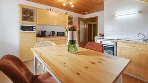 Een houten keuken met een eettafel, een magnetron, een koffiezetapparaat en een vaas met bloemen.