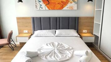 A modern hotel room with a large bed, two bedside tables, a chair, and a wall-mounted artwork.