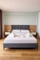 A modern hotel room with a large bed, wooden headboard, and two bedside tables.