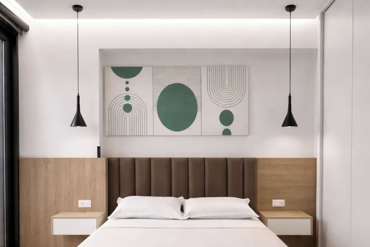 A modern bedroom with a large bed, wooden headboard, two bedside tables, and abstract wall art.