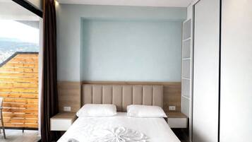 A modern hotel room with a large bed, a wooden ceiling, and a view of the city.