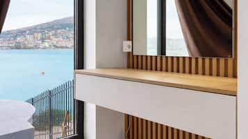 Una habitación moderna con un ventanal grande, un panel de pared de listones de madera, un espejo y un taburete redondo.