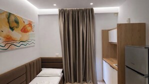 Ein kleines Zimmer mit Bett, einer Küchenzeile und einer Dusche.