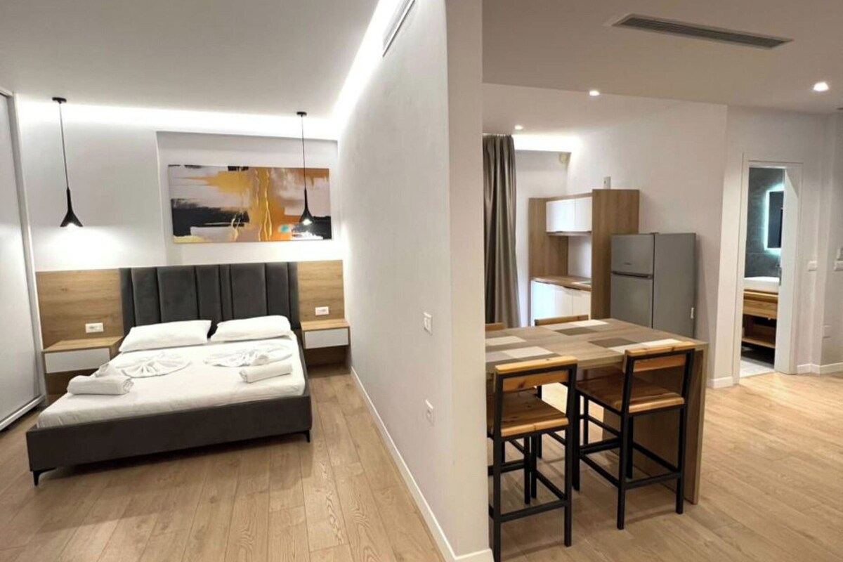 A modern bedroom with a bed, bedside tables, and a desk area with chairs.