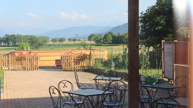 Une terrasse extérieure avec des tables et des chaises, une clôture en bois et une vue sur les montagnes en arrière-plan.