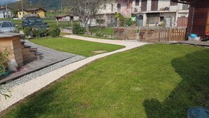 Une pelouse bien entretenue, avec un chemin de gravier menant à une terrasse en bois.