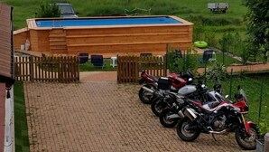 Une allée pavée en briques mène à un bâtiment en bois doté d’une piscine.