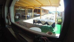 Un espace extérieur abrité, aménagé pour les repas, avec des tables et des chaises, une piscine et une vue sur le paysage environnant.