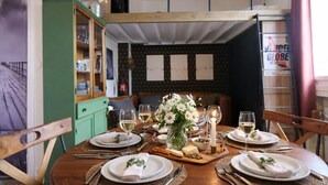 Una mesa de comedor servida con platos blancos, copas y un centro de mesa con flores blancas.