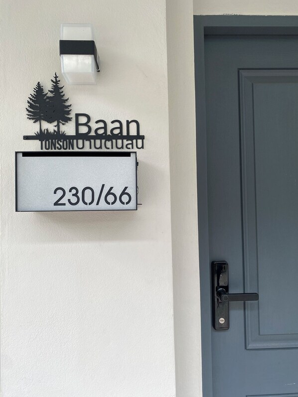 Une plaque indiquant le numéro de la maison, avec les mots « Baan » et « TONSONOTUCUADU » écrits au-dessus, et le numéro « 230/66 » en dessous.