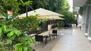 An outdoor patio area with a beige umbrella, black wicker furniture, and a tiled floor. - Le Stanze dell'Emiro (Palermo)