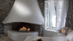 Um quarto aconchegante com lareira de pedra, uma cama confortável e uma janela com cortinas.