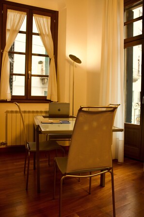 Ein Zimmer mit Holzboden, einem Tisch mit Laptop, einem Stuhl und einer Heizung.