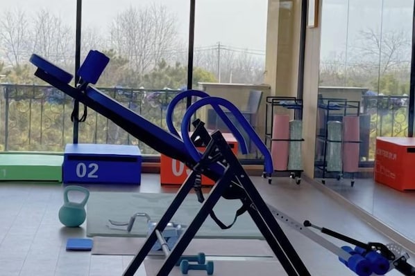 A gym with exercise equipment, including a treadmill, weights, and a kettlebell. - Yangzhou Rundfel Manor (Yizheng)
