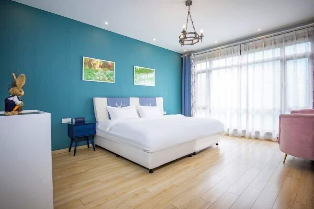 A bedroom with a bed, a nightstand, a dresser, a chair, and a window with curtains.