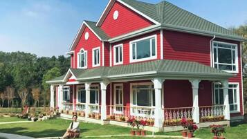 A two-story house with a red exterior and a grey roof.