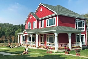 A two-story house with a red exterior and a grey roof.