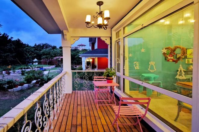 A wooden deck with a railing, a table, and chairs.