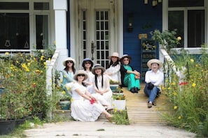 A group of people seated on a wooden porch with a garden in front. - Yangzhou Rundfel Manor (Yizheng)