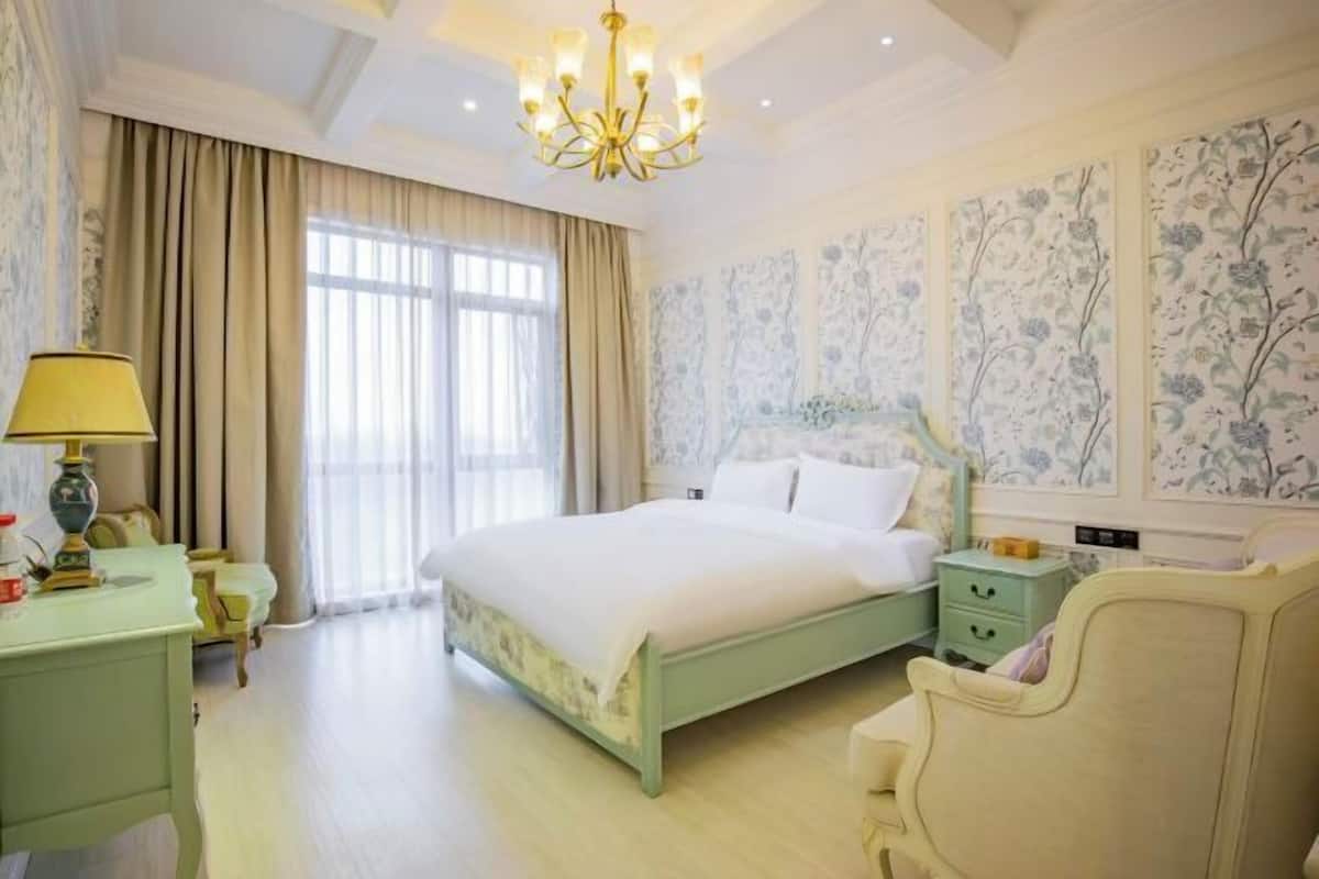 A bedroom with a bed, nightstands, a chair, a lamp, and a window with curtains.