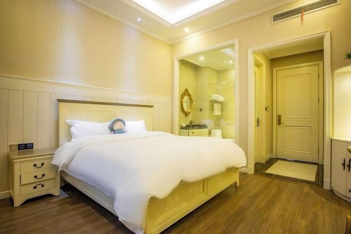 A hotel room with a bed, bedside table, and a mirror.