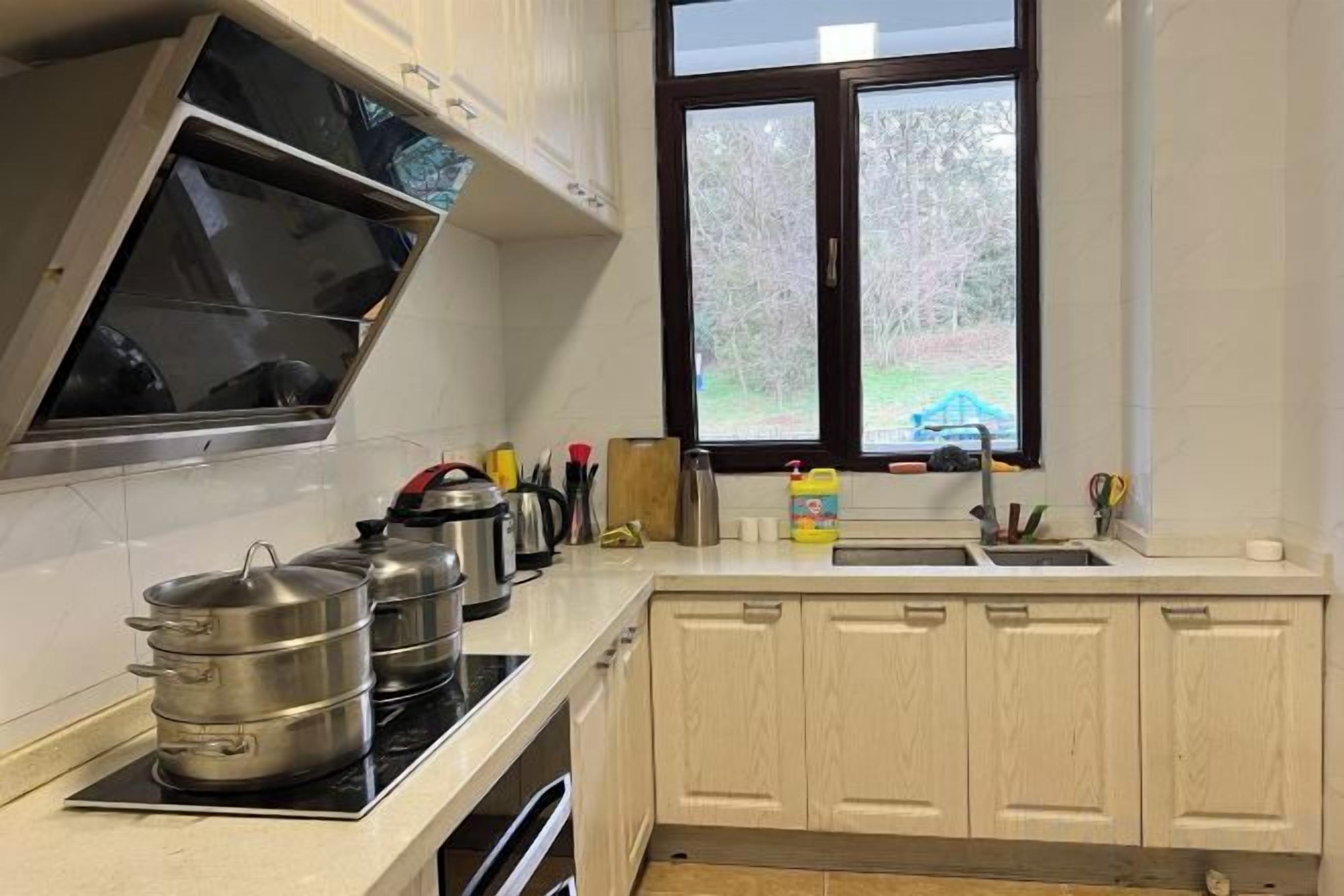 A kitchen with a stove, pots, a window, and a sink.